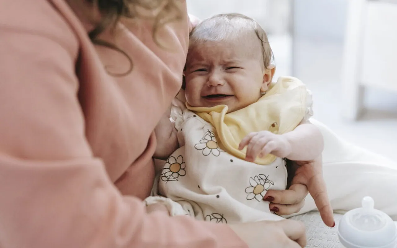 Parent using a connected infant monitoring device in a softly lit nursery